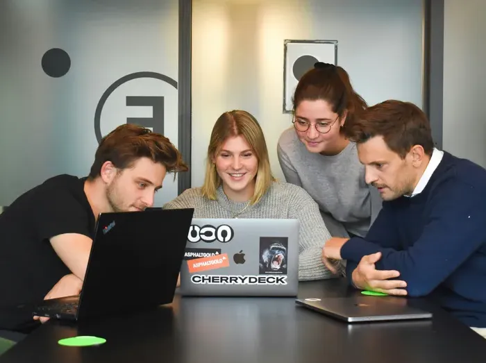 Four team members around laptops planning local services, office meeting shot, Why Choose Us image